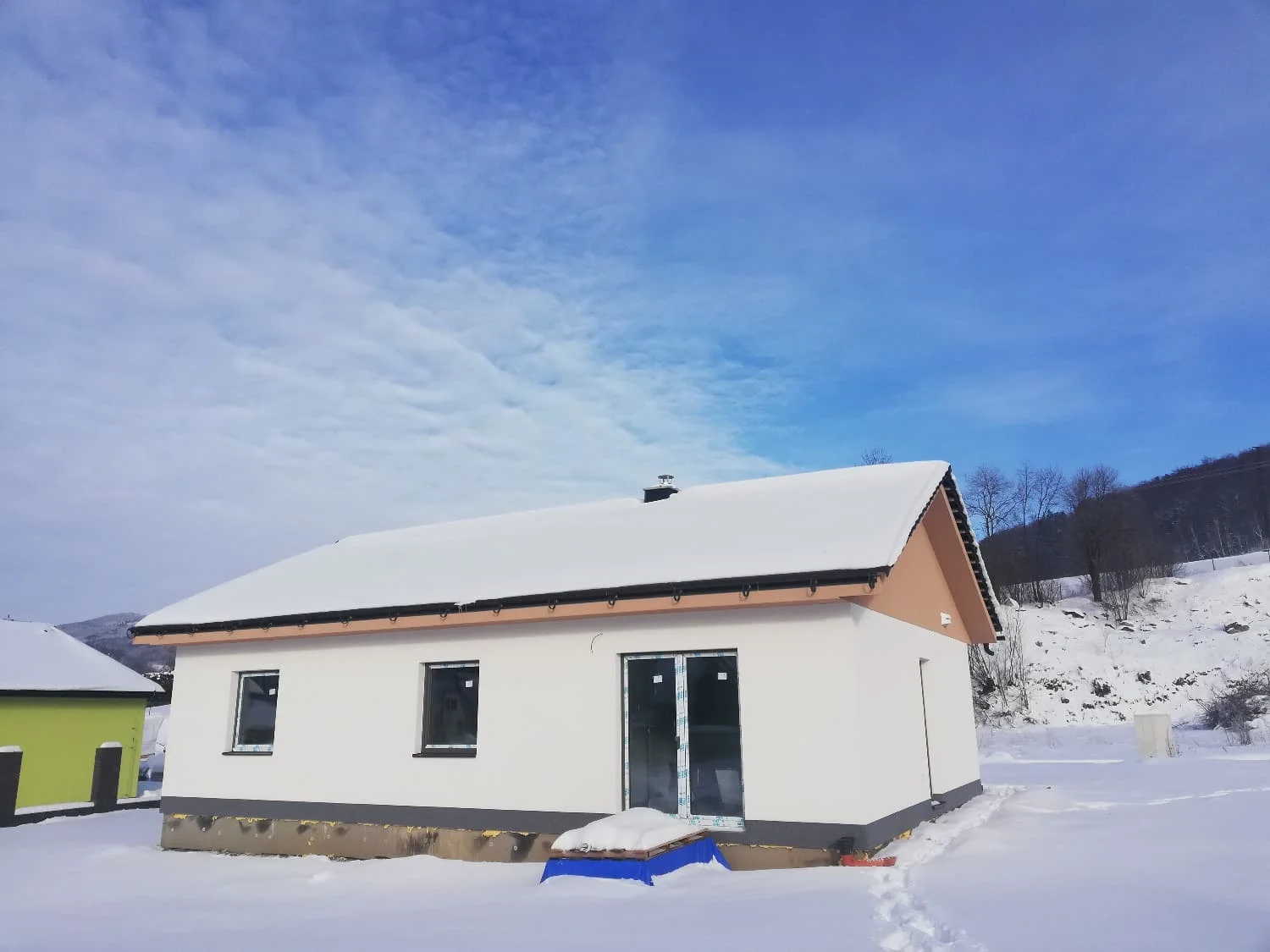 Rodinný bungalov s dokončenou bílou fasádou v zimě